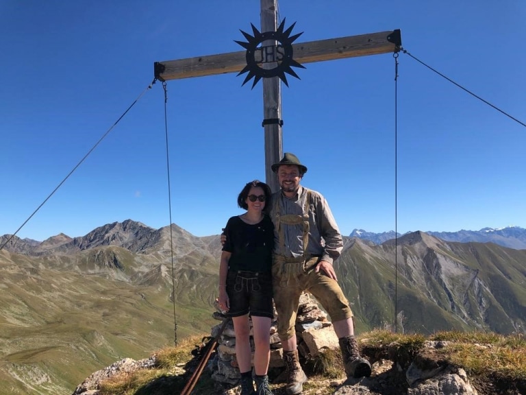Paar posiert vor Gipfelkreuz