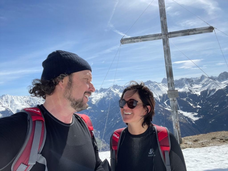 Mann und Frau vor Gipfelkreuz und Bergpanorama