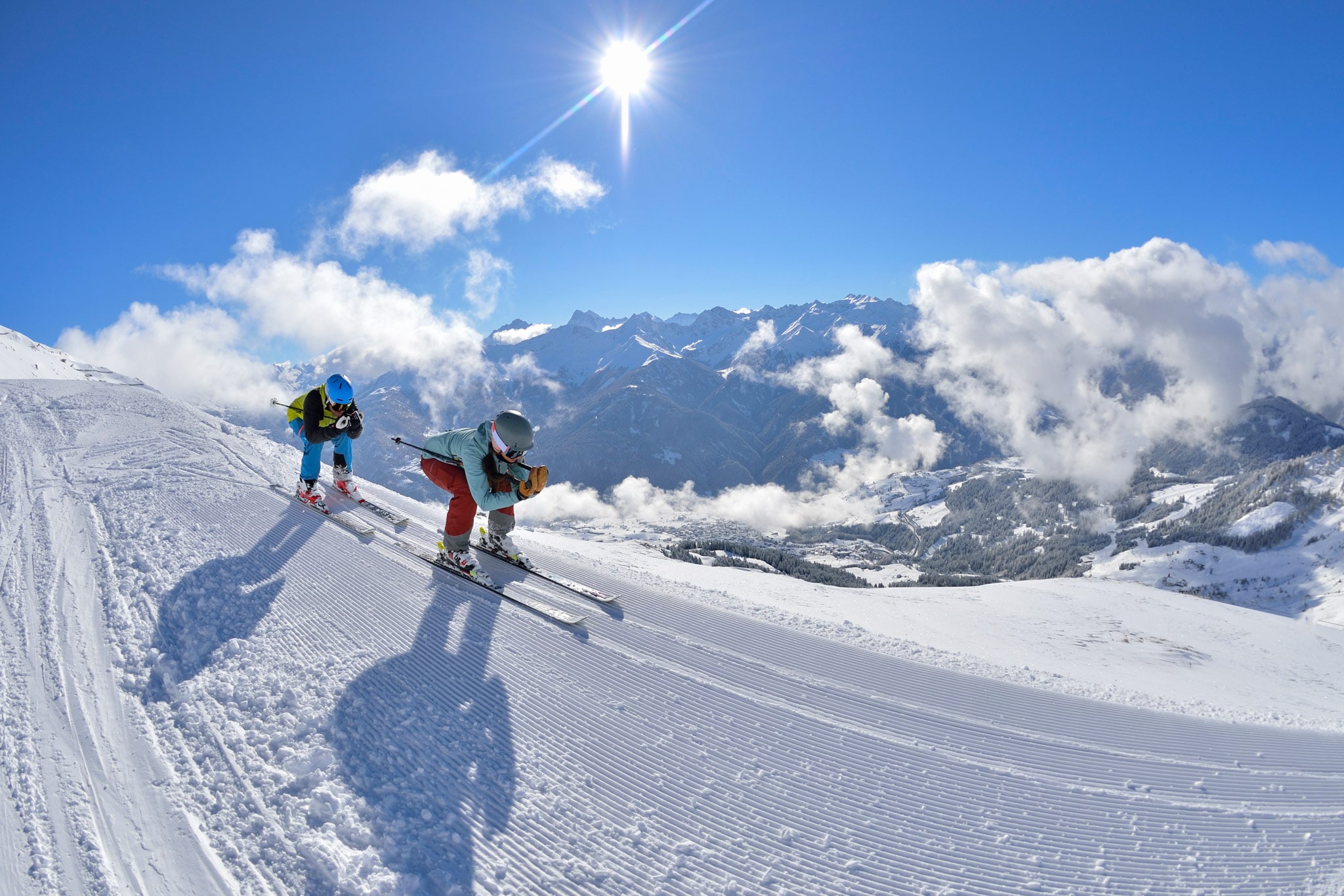 Zwei Skifahrer fahren in der hocke auf einer Piste