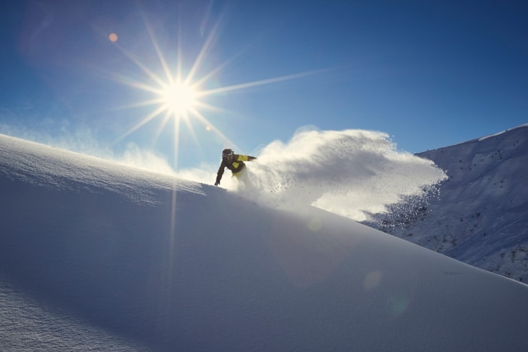 Ein Snowboarder fährt im Tiefschnee nach unten