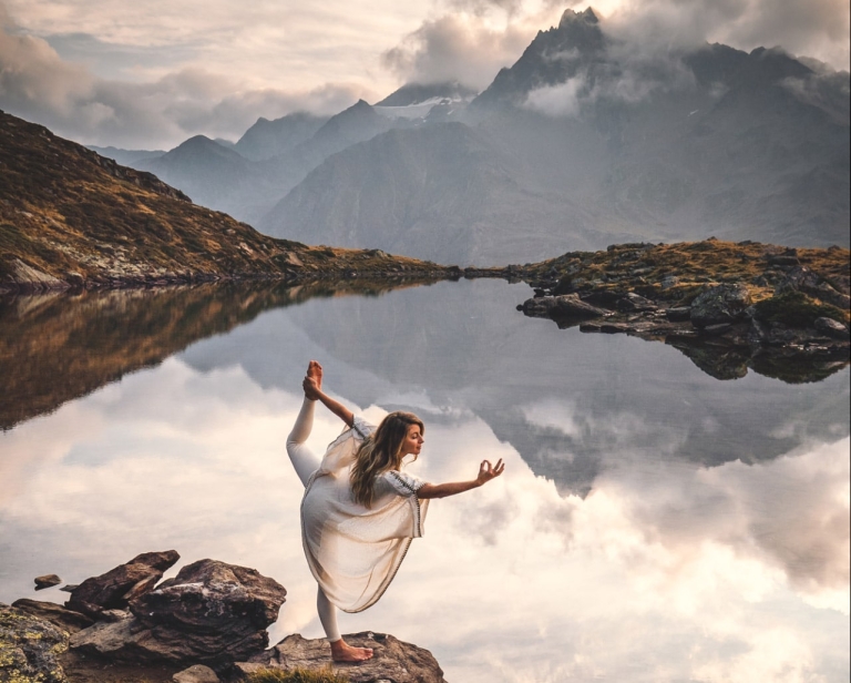 Eine Frau macht Yoga bei einem Bergsee