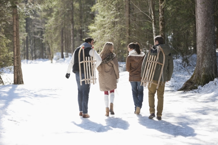 Freunde tragen Rodeln durch den Schnee