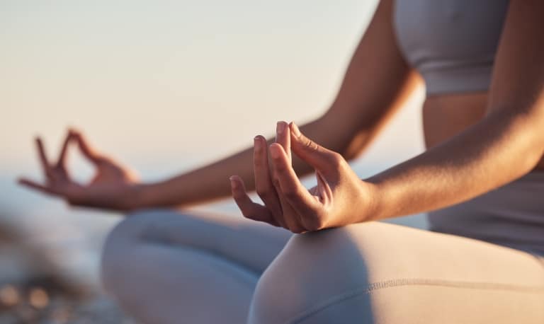 Nahaufnahme der Hände bei der Meditation im Schneidersitz