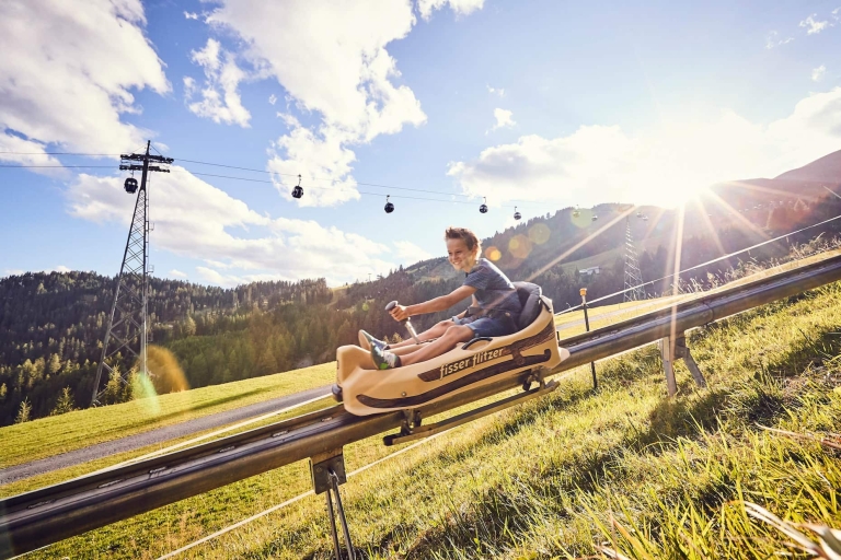 Kind fährt auf der Sommerrodelbahn Fisser Flitzer in Tirol den Hang hinab