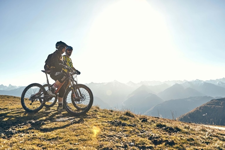 Zwei Radfahrer blicken in Ihrem Mountainbikeurlaub in Tirol auf die umliegenden Berge