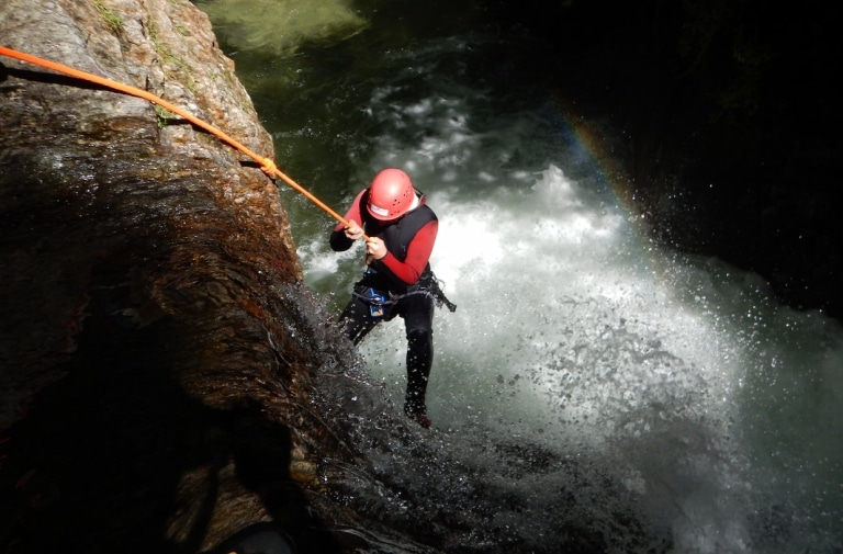Kletterer beim Canyoning in Serfaus-Fiss-Ladis. Unter ihm wir das Wasser nach oben gespritzt.